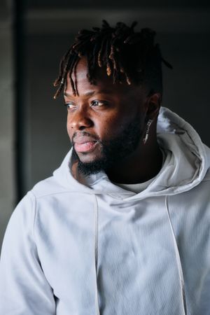 Black man with dreadlocks in fancy outfit looking away