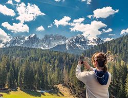 Woman in down vest taking photo of amazing landscape