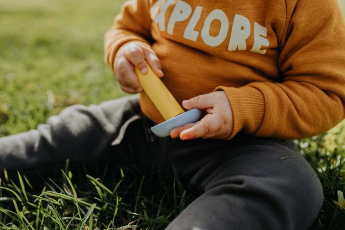 Close up of toddler sitting in park with toys