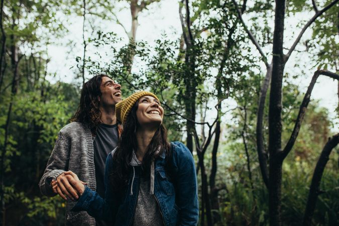 Happy young couple holding hands while observing a forest