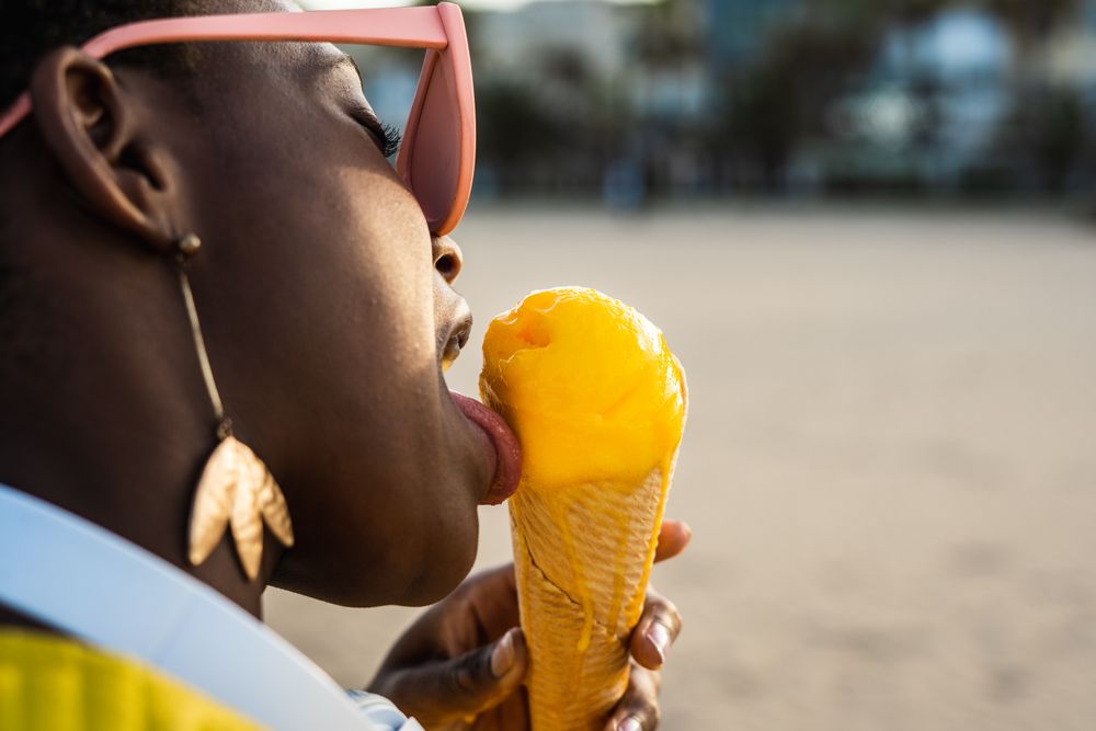 Cool female eating ice cream on beach