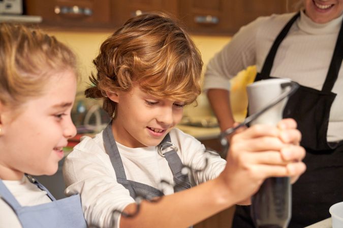 Children using blender near faceless mother