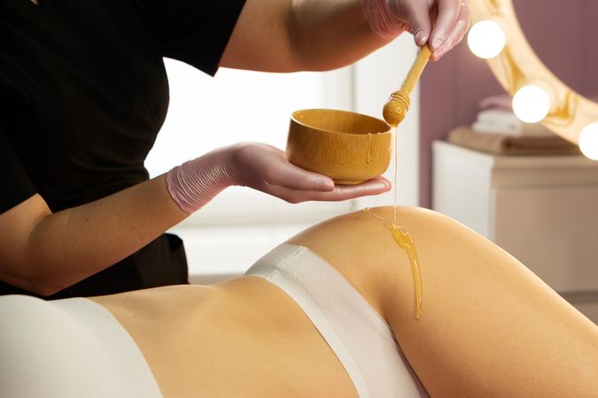 Honey flows smoothly from dipper during wellness skin treatment.