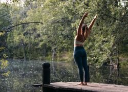 Woman in sportswear doing yoga outdoors near a lake