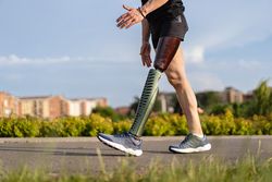 Low angle view at man with prosthetic leg walking along the a path in the park