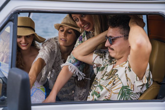 Group of women showing road on map in hands of man in car
