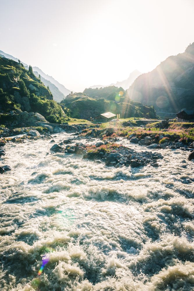 Foamy mountain stream flowing through stones in sunlight