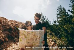 Man and woman holding a navigation map while hiking in a forest 4B6wk4