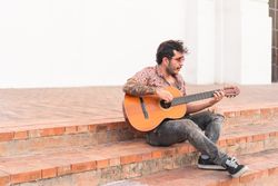 Street musician playing guitar on a staircase in the street