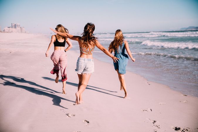 Group of young women running along the sand at the beach