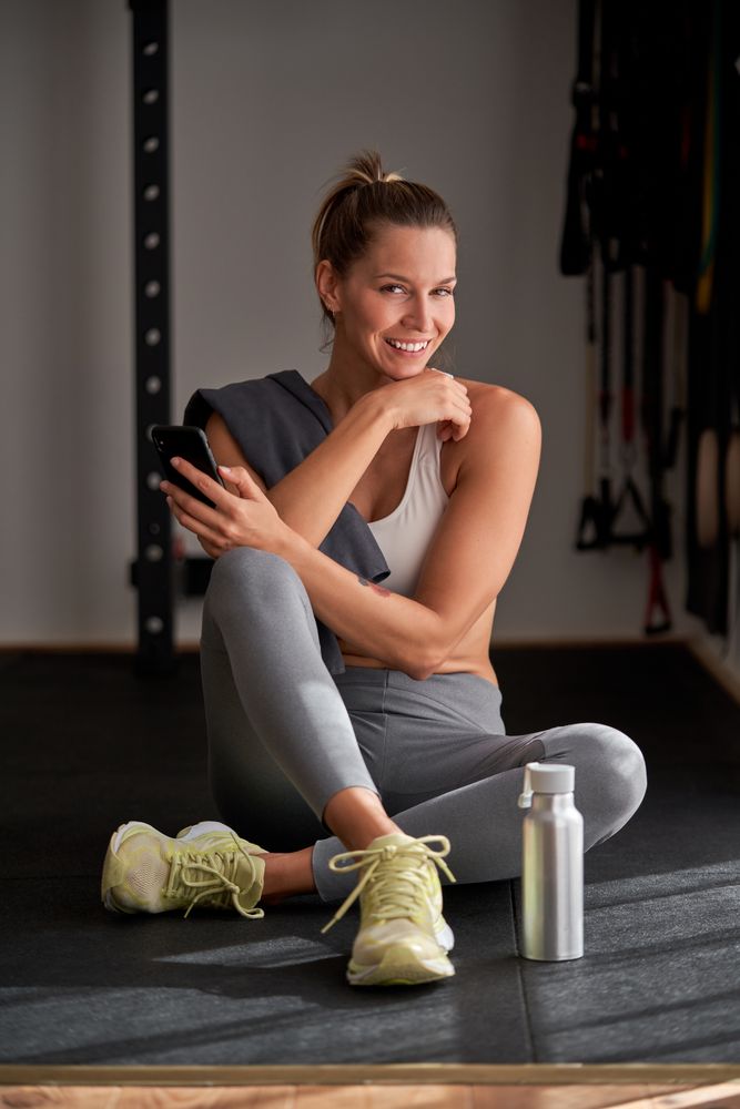 Smiling woman with smartphone in gym