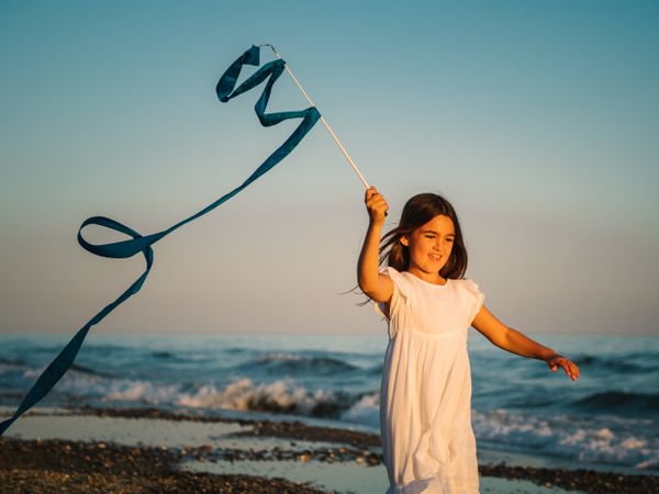 Adorable girl playing with ribbon on seaside