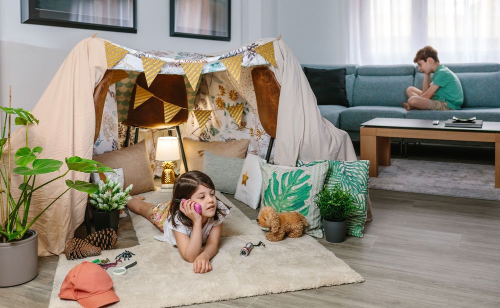 Two happy children talking with walkie-talkie at in cozy tent. Vacation camping at home concept.