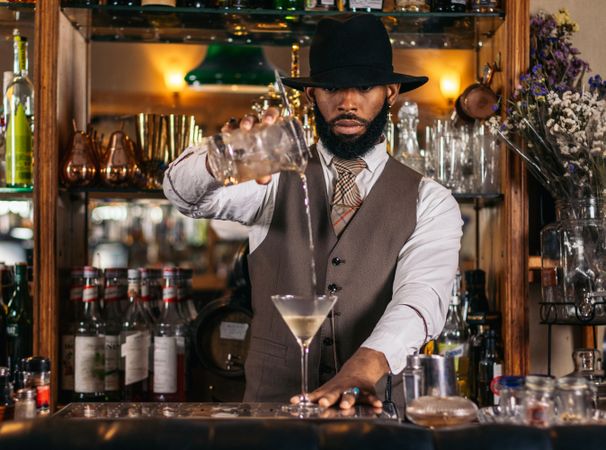 Black bartender preparing a cocktail in a traditional cocktail bar