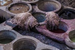 Heaps of dirty textile near containers with colorant liquid