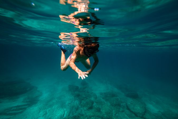 Teen boy snorkeling in deep seawater in flippers and mask