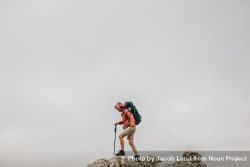 Woman wearing backpack hiking up a rocky hill 0KEYN4