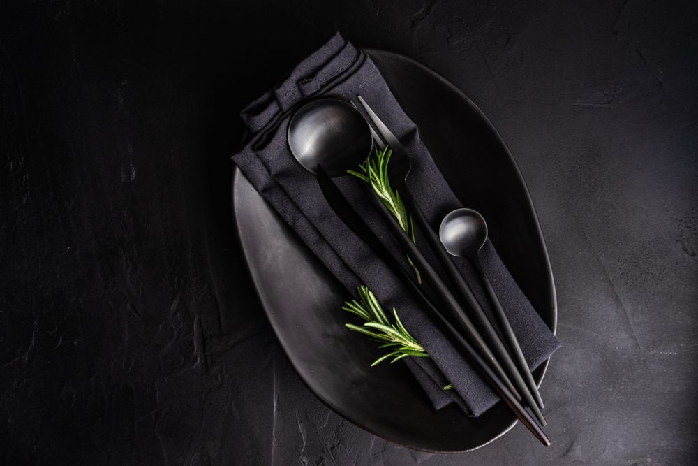 Sleek table setting in dark color with rosemary sprig and copy space