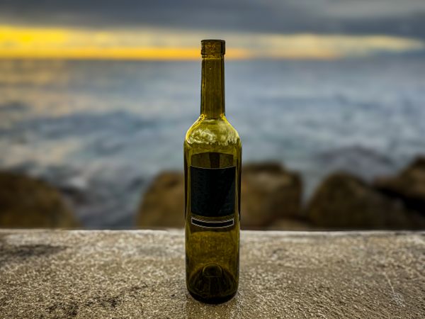 Bottle of wine on wall overlooking rugged coastline