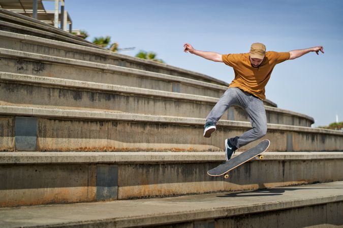 A young man doing an ollie 360 flip with his skateboard on some bleachers