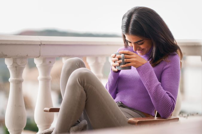 Female laughing outside on patio with a cosy warm drink