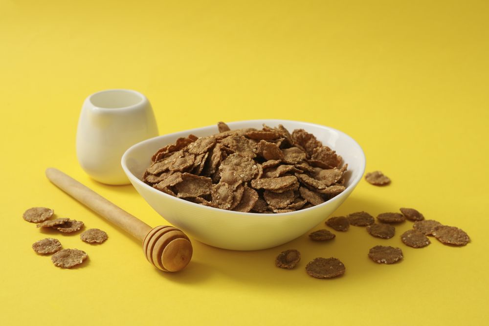 Dipper and bowl of muesli on yellow background