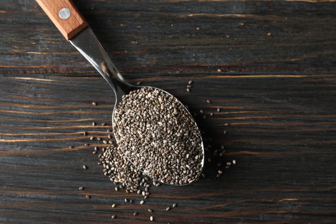 Spoon with chia on wooden background, copy space