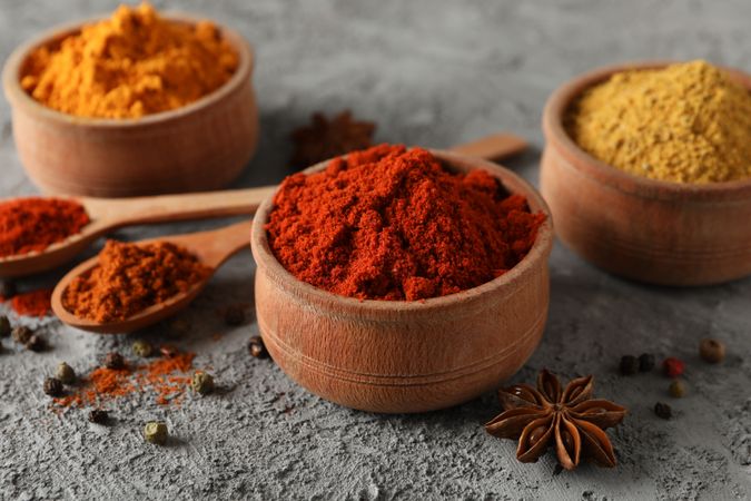 Side view of wooden bowls with red, yellow and brown spices