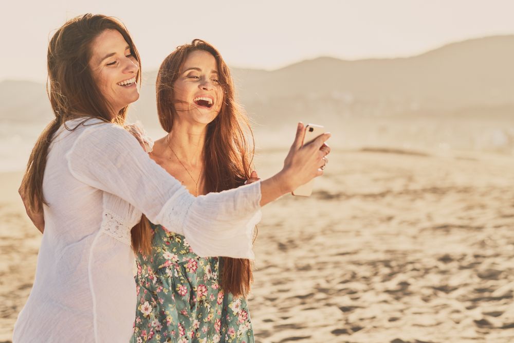 Smiling women making selfie on beach