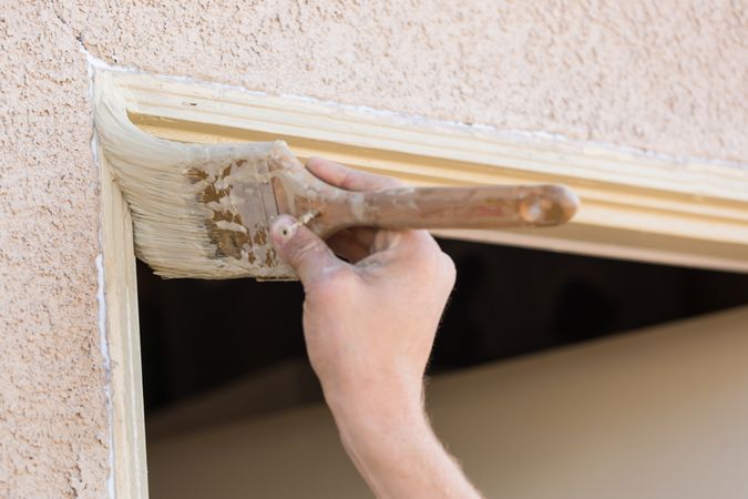 Professional Painter Cutting In With Brush to Paint House Door Frame.