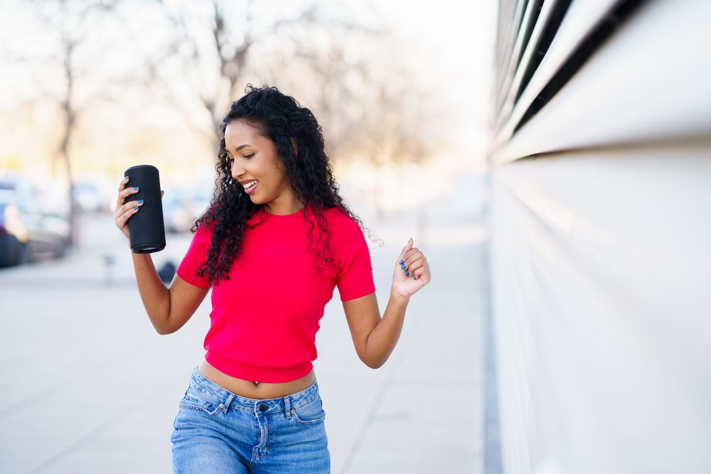 A Young Woman Joyfully Enjoys Music Outdoors in a Trendy Outfit, Reflecting Freedom and Fun