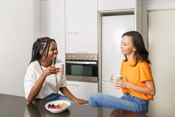 Two women laughing together and having breakfast in the kitchen