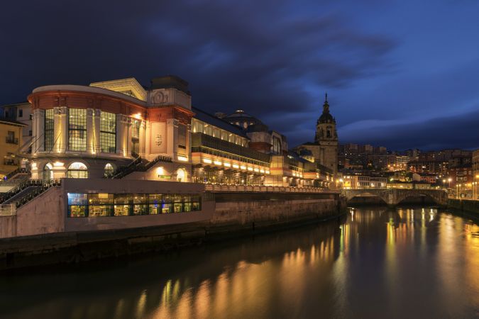 City riverbank with glowing buildings in evening