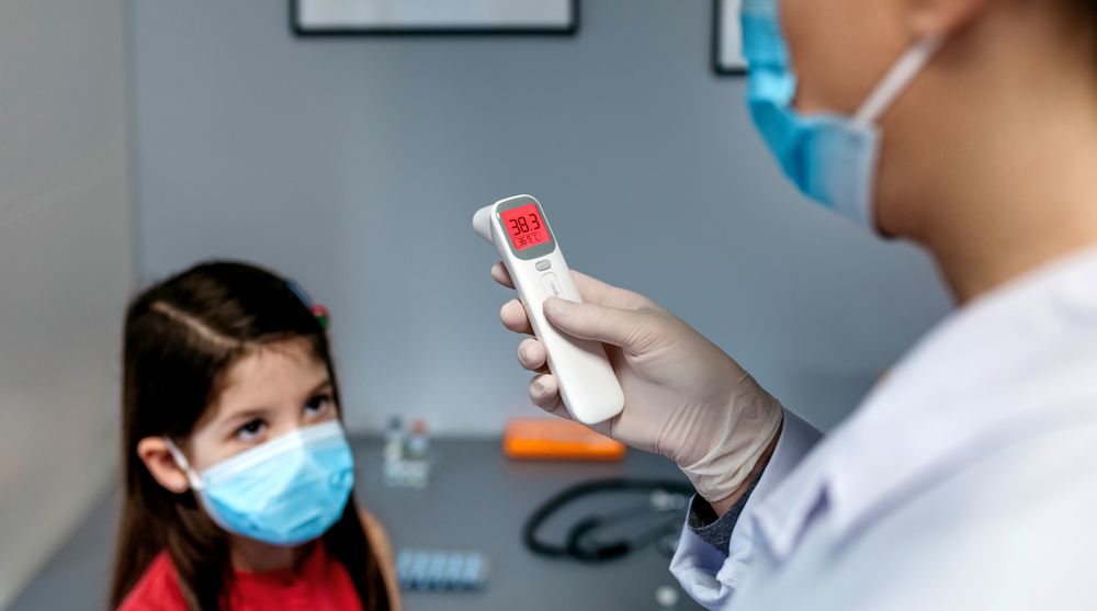 Female doctor looking at infrared thermometer after taking temperature to a girl