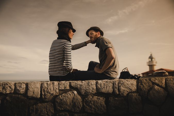 Man and woman on stones near lighthouse