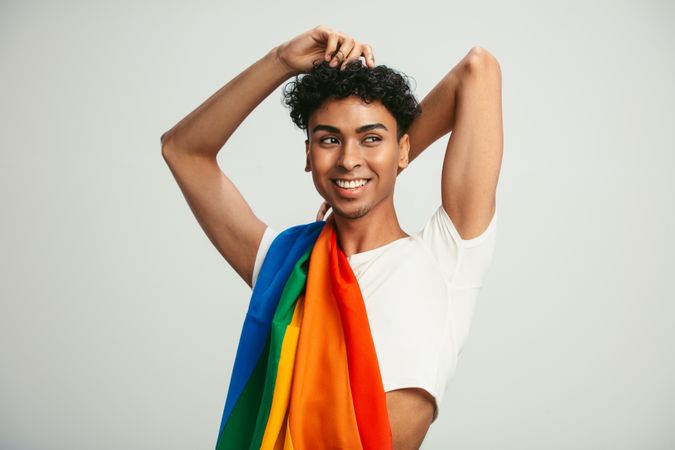 Man with a rainbow flag on his shoulder looking away