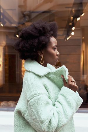 Side view of woman in turquoise jacket standing outdoor