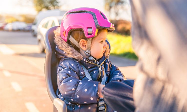 Baby in pink helmet on the back of a bike