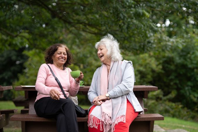 Two mature women sitting outside sipping tea