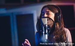 Closeup of woman recording a song for her new album in recording studio 5nPnDb