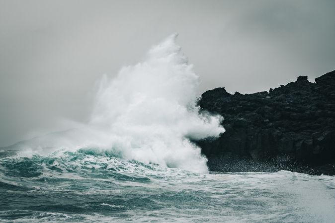 Waves crashing into the dark rocks of Iceland’s coast