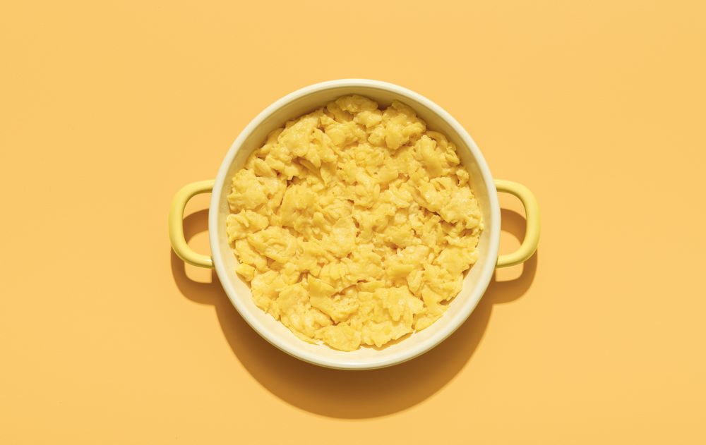 Scrambled eggs above view minimalist on an orange background