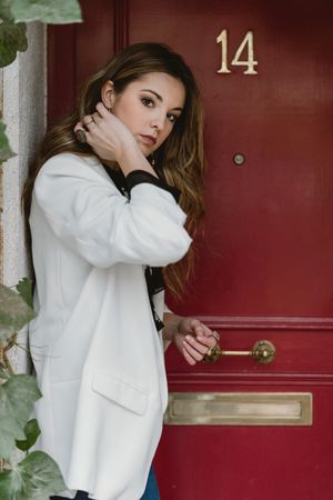 Stylish woman standing near red door