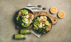 Two vegetarian bowls,  with smoothie, on placemat, bread board