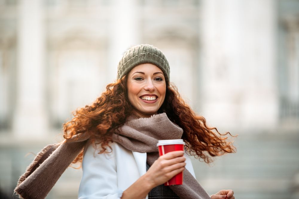 Woman drinking coffee dancing in the streets of Madrid on winter