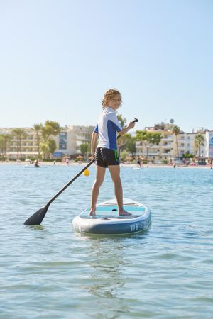 Child on SUP board floating in sea during training