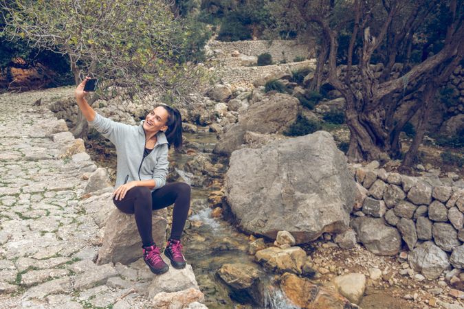 Cheerful female traveler taking selfie on smartphone