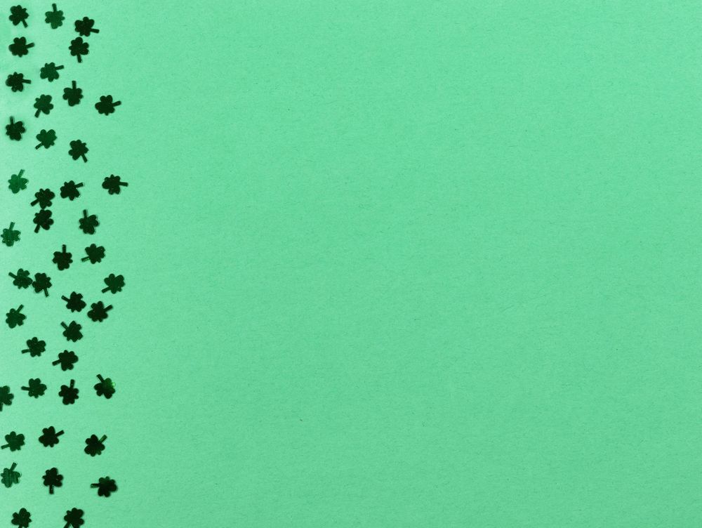 St Patrick’s Day border of Shamrocks on light green paper background
