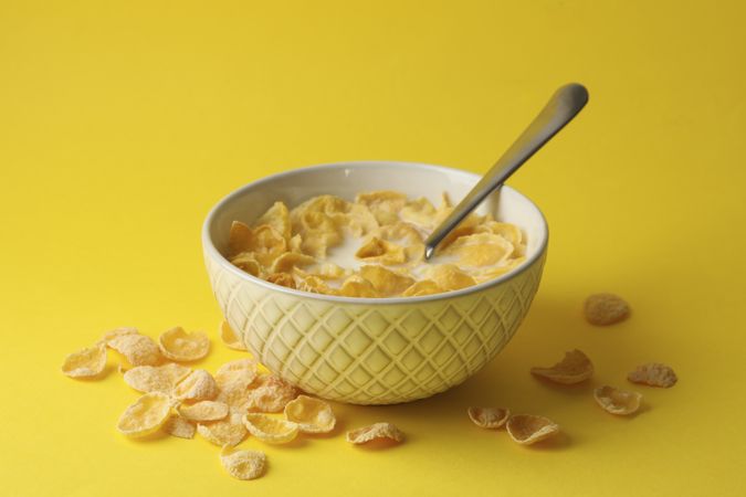 Bowl with muesli and milk on yellow background
