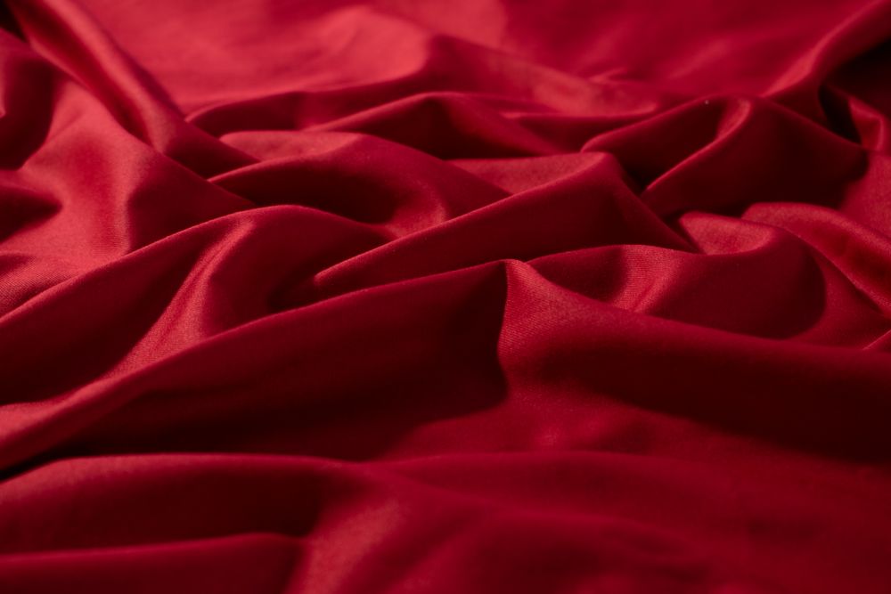 Crumpled wavy Red silky fabric background texture.